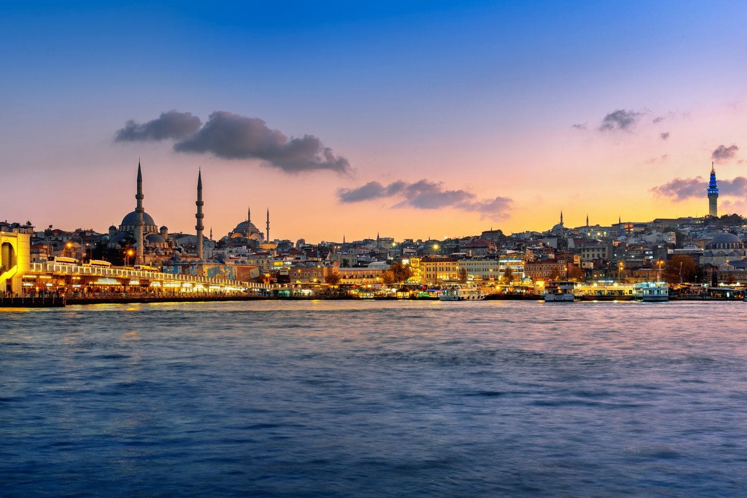 A view of Istanbul at sunset, with city lights twinkling and the Bosphorus stretching across the horizon