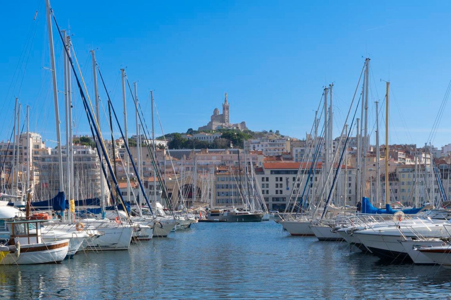 A view of Marseille's port, filled with boats, against the backdrop of the city skyline