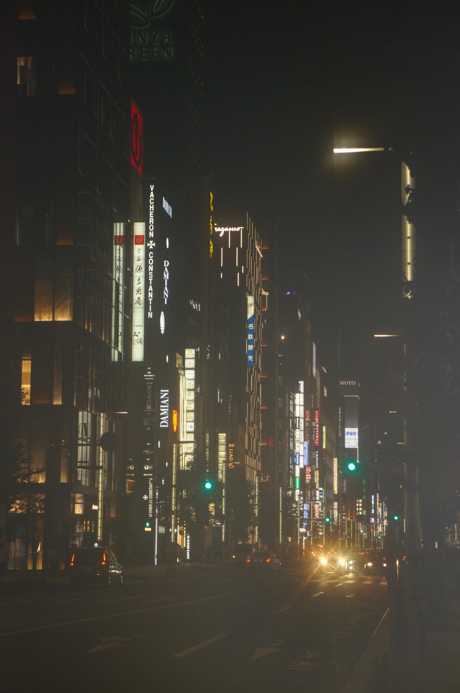 Commercial city buildings on a street in Ginza, Tokyo are lit up at night