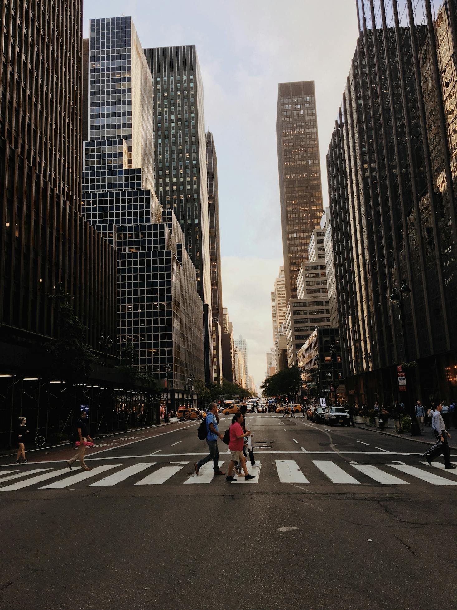 People crossing the street in front of highrises in busy Manhattan, New York