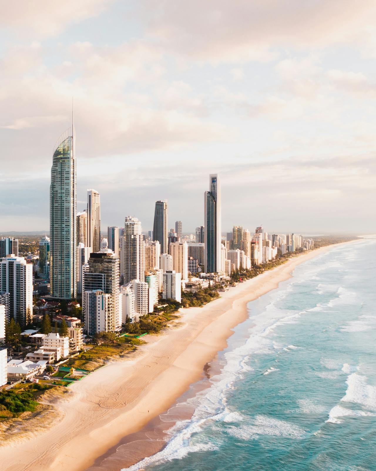 The shoreline of Gold Coast with tall buildings and golden sand The shoreline of Gold Coast with tall buildings and golden sand