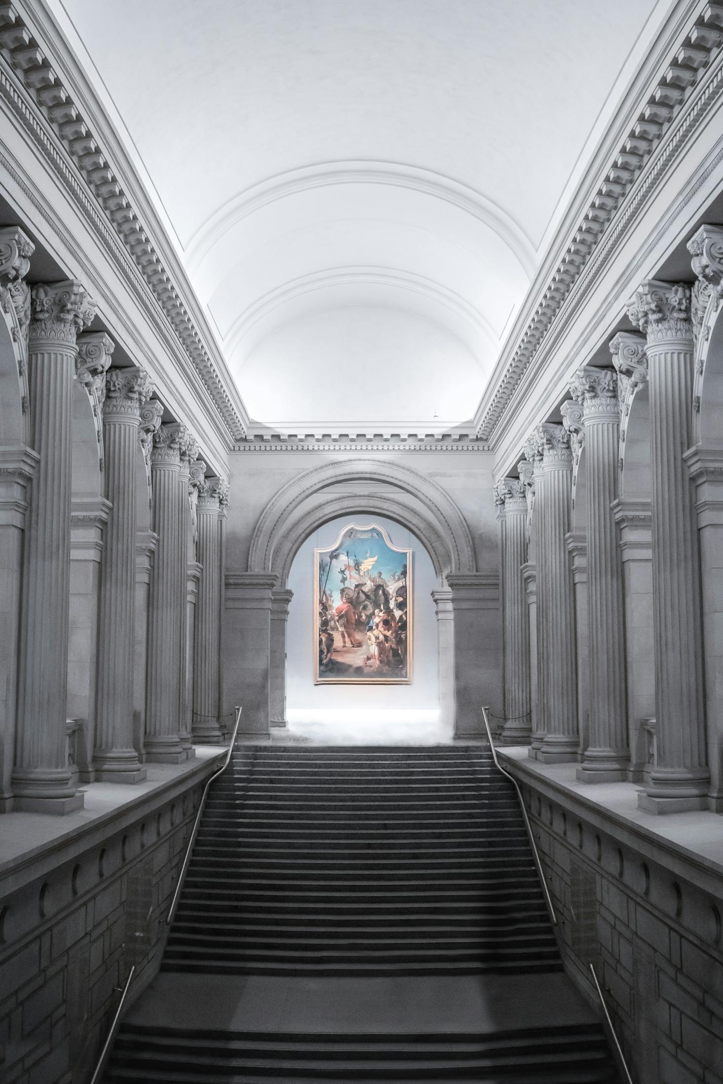 An ornate gallery at the Metropolitan Museum of Art in NYC with columns leading to a painting