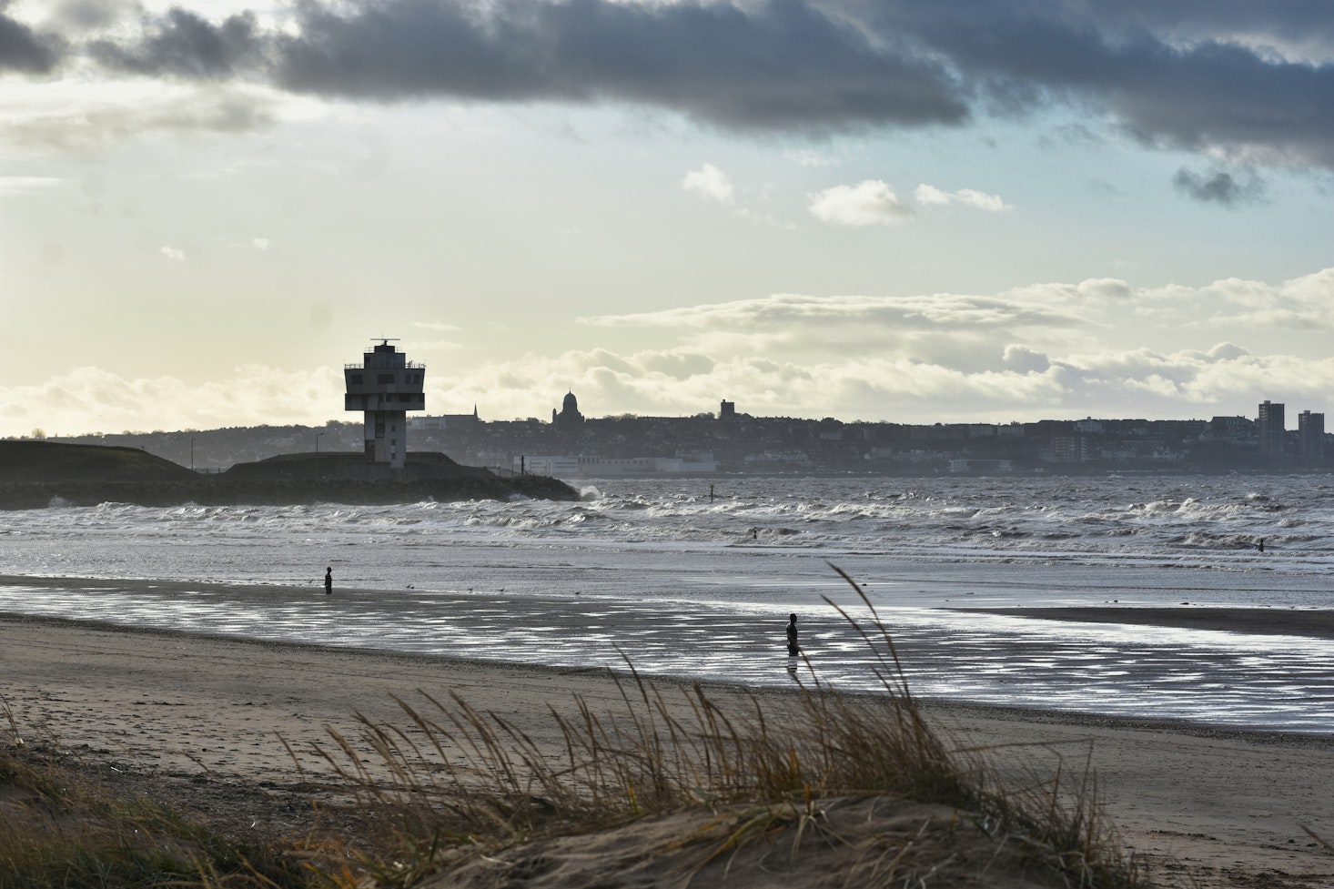 One of the beaches near Liverpool on a gloomy day overlooking the sea and lighthouse in the distance