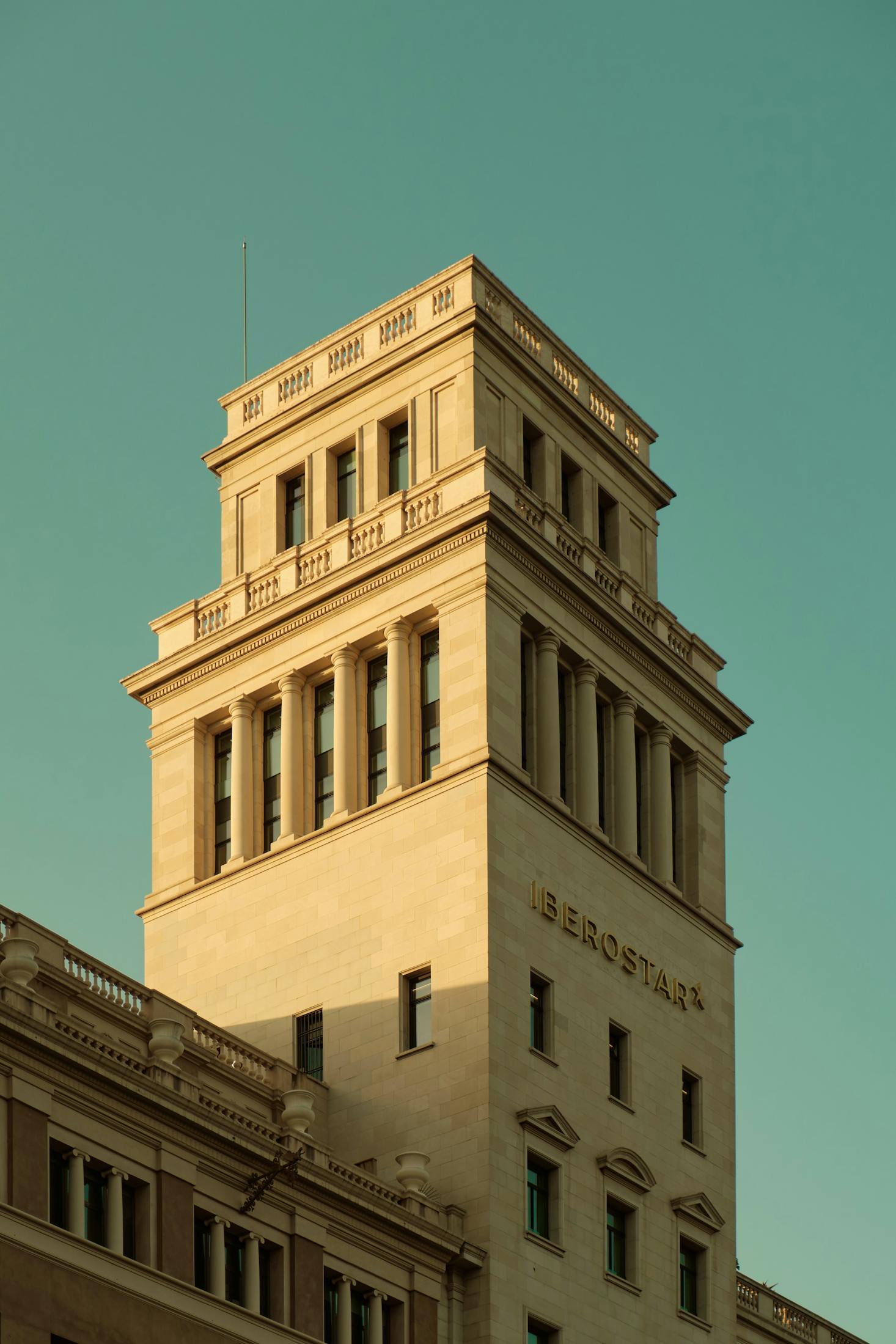 A white washed tower with blue sky behind it in Barcelona's Placa de Catalunya