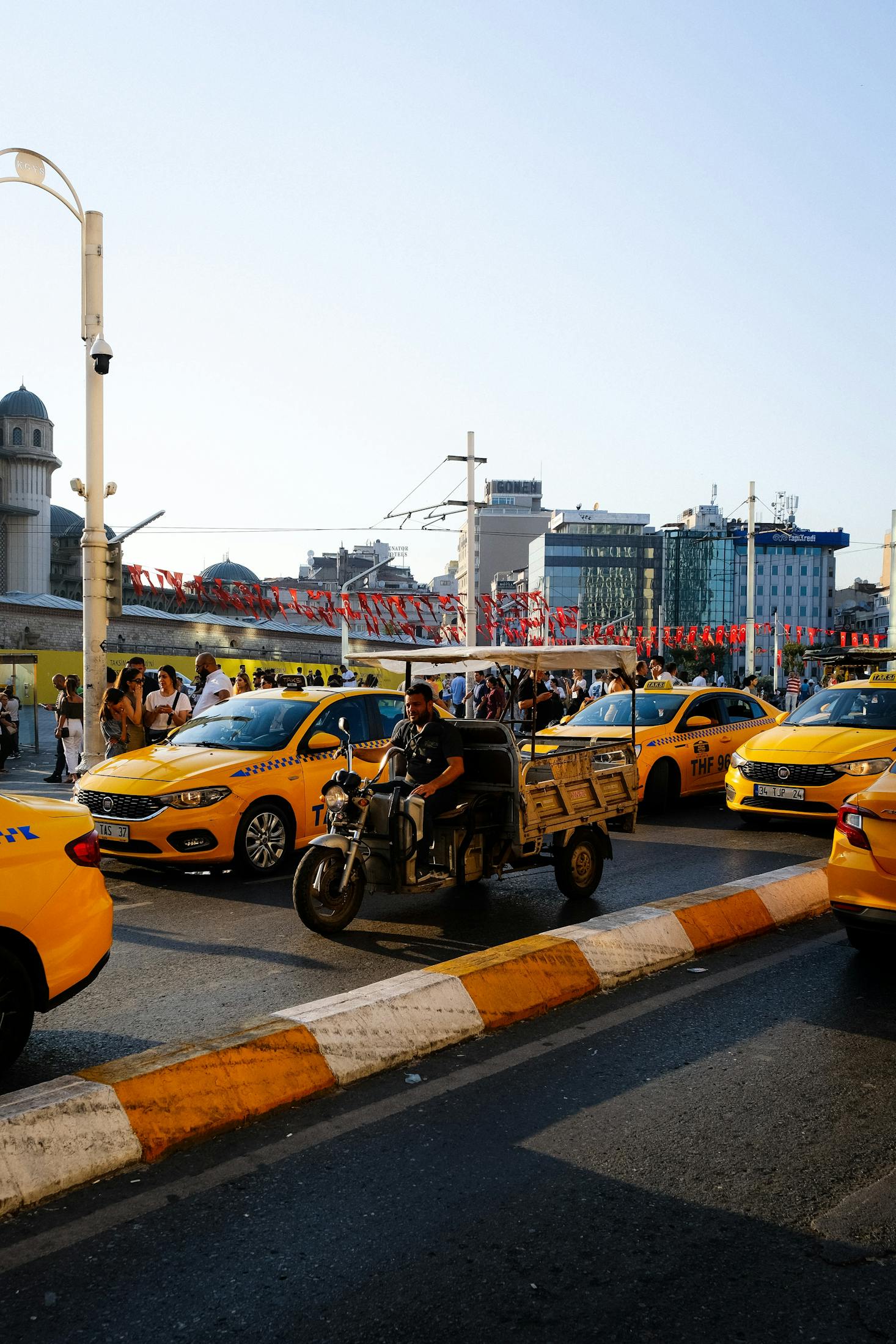 A crowded road with a motorbike and yellow taxis near Istanbul's Taksim Square