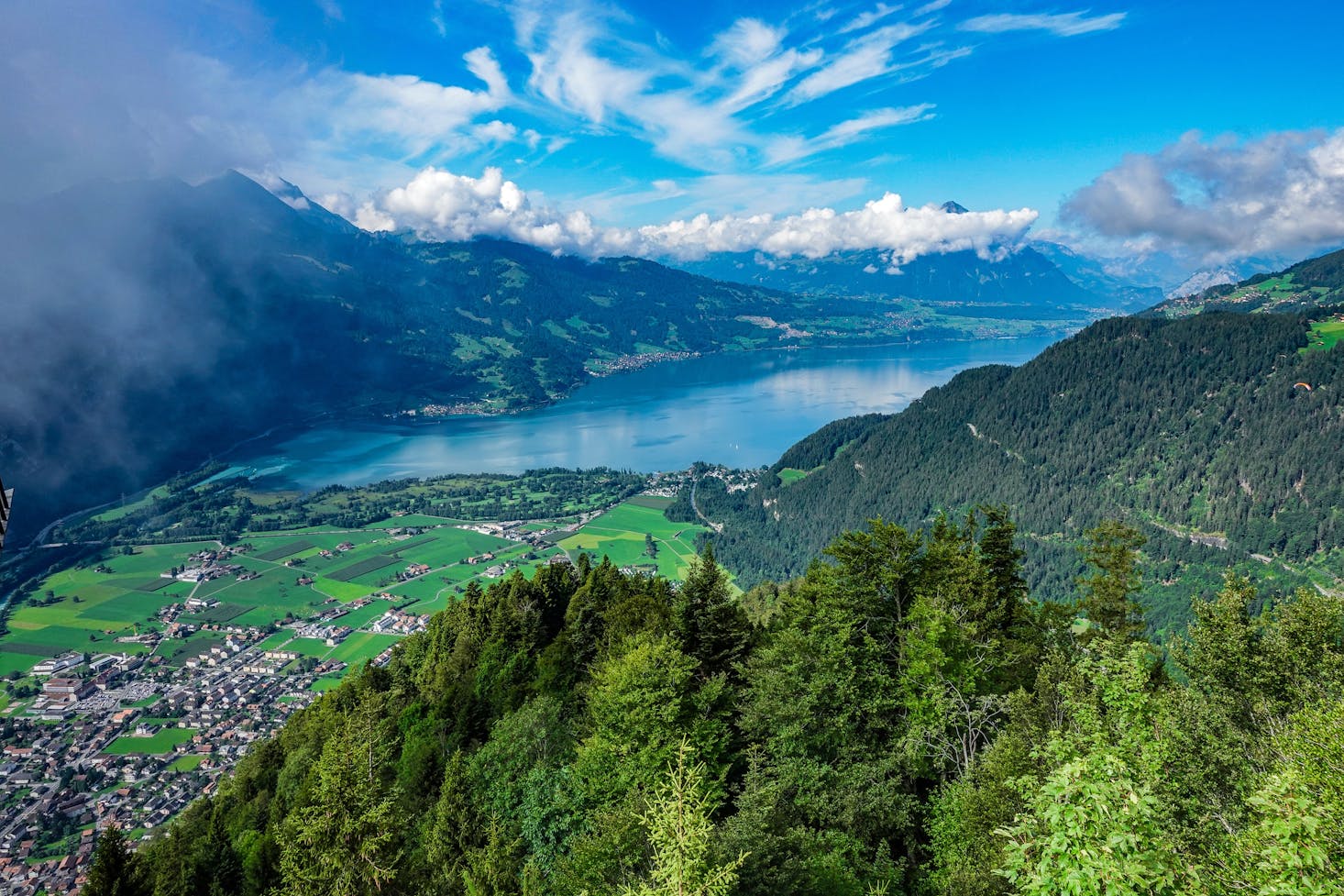 The picturesque green meadows, mountains, and lakes surrounding Interlaken