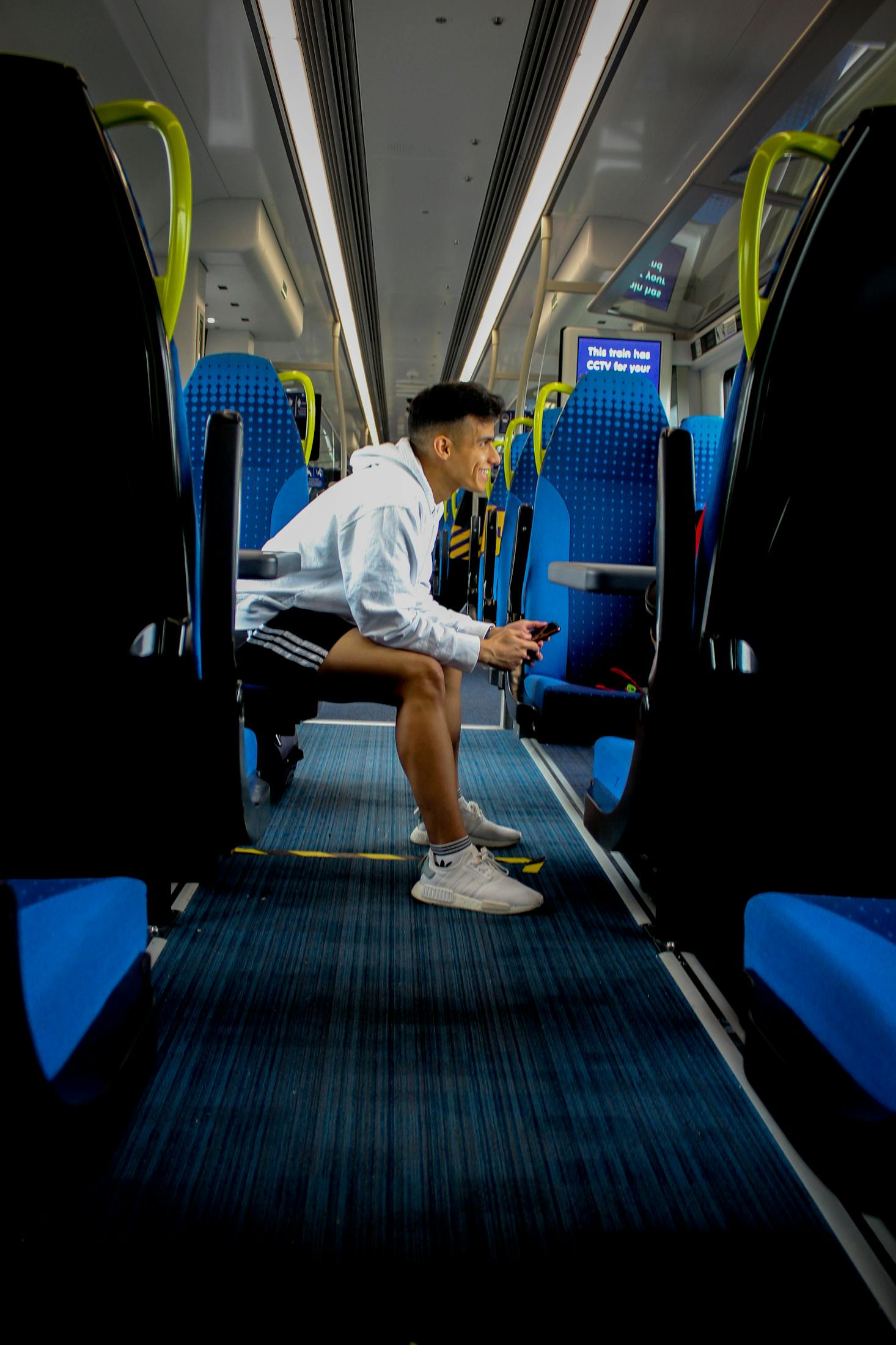 Person sitting on a blue train seat at Manchester Piccadilly Station