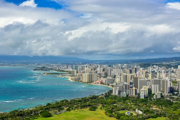 Aerial view of the coast off Honolulu with green space, ocean, and skyscrapers