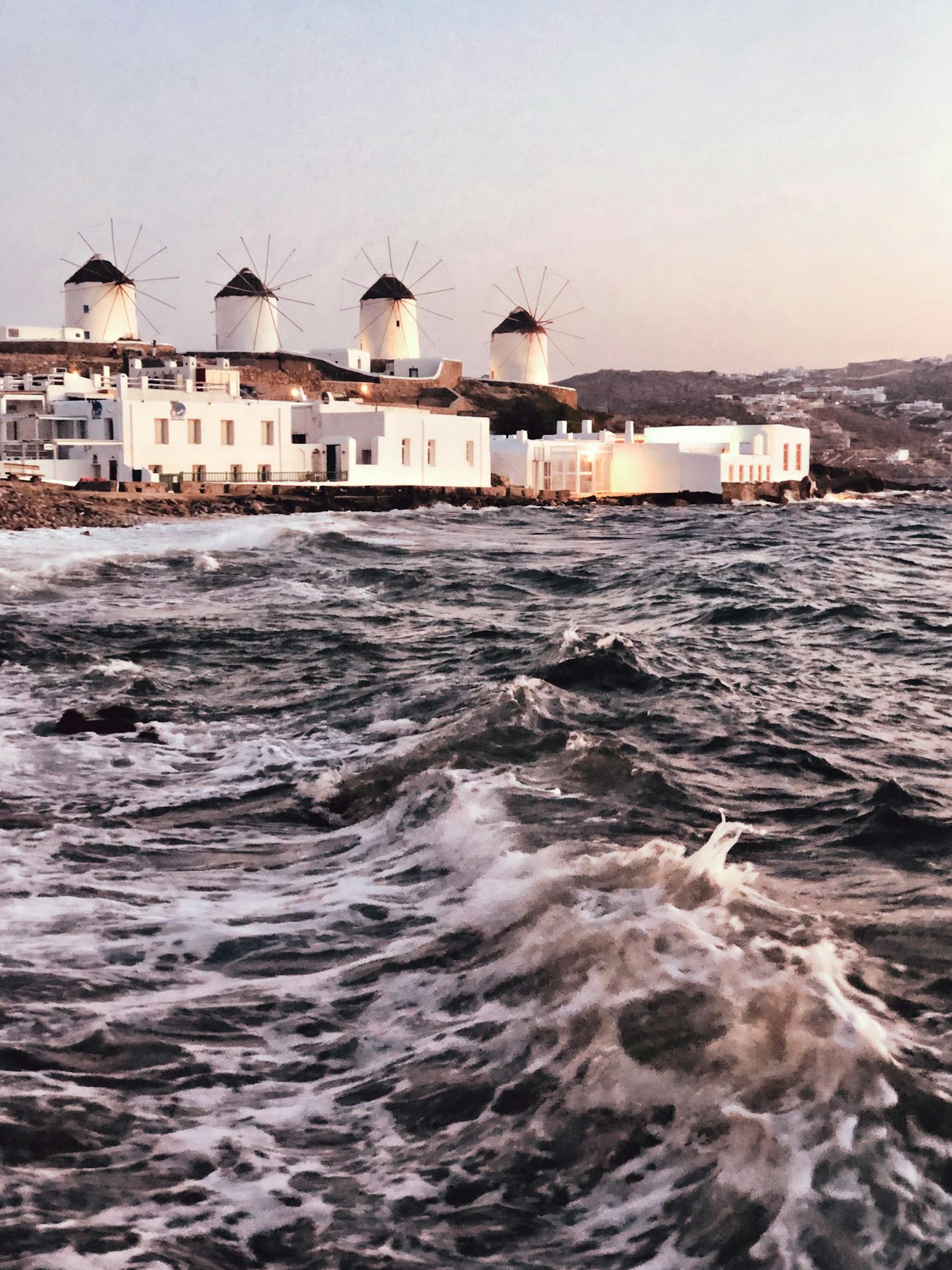 Mykonos Old Port, Greece with a rough sea and white buildings in the distance