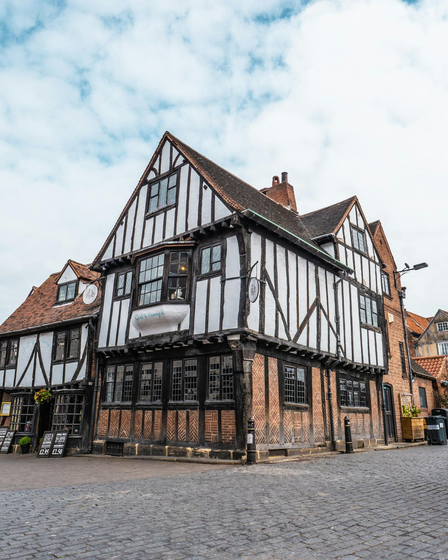 A white and brown half-timber building on a cobblestone street in York