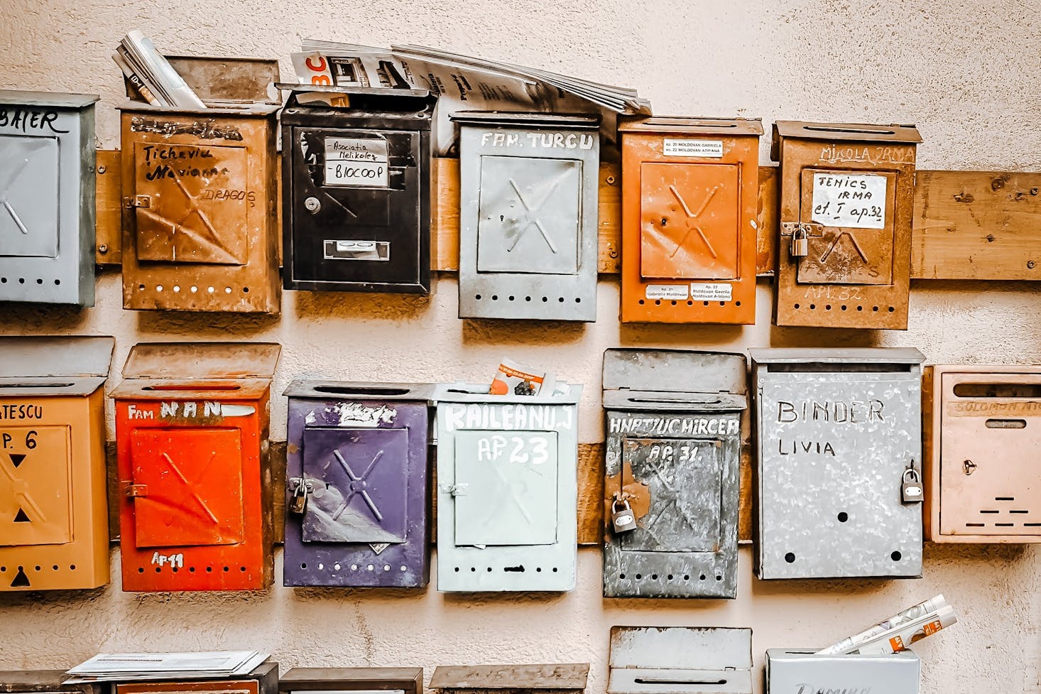 Many mailboxes of different colours stacked up next to one another