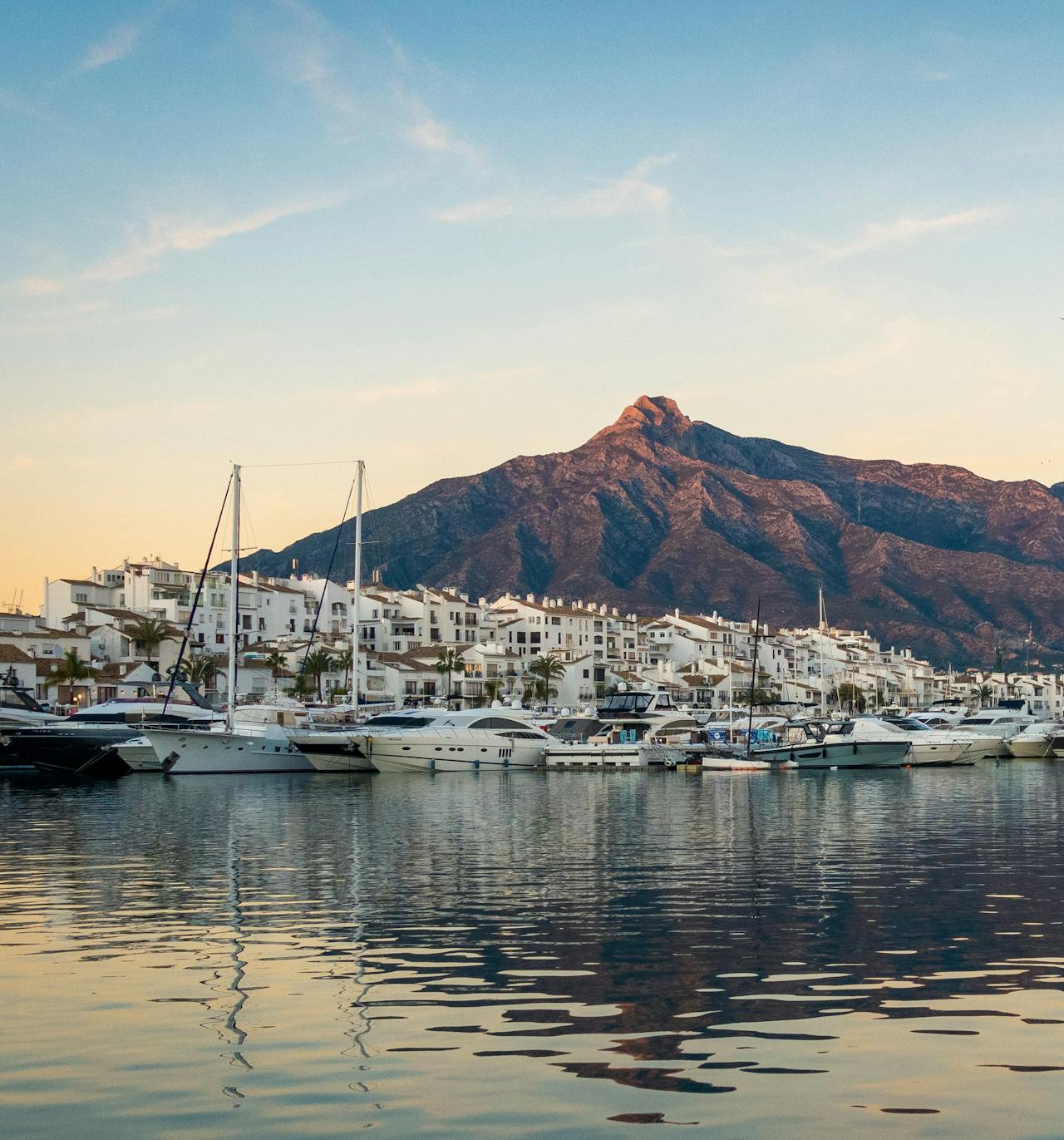 The marina in Marbella at sunset with a mountain in the distance