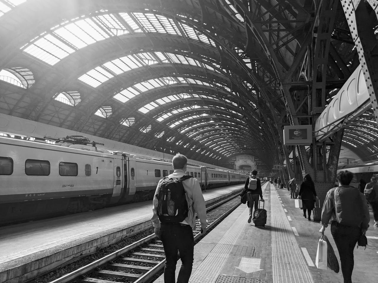 Viaggiatori camminano sui binari all'interno della stazione di Milano Centrale