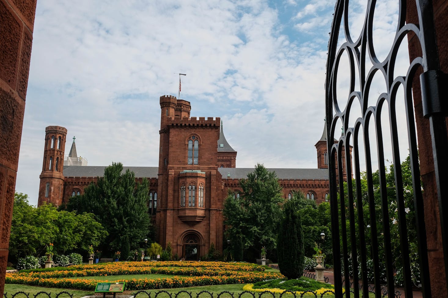 An exterior picture of The Smithsonian Castle, Washington D.C., peering in through the gates
