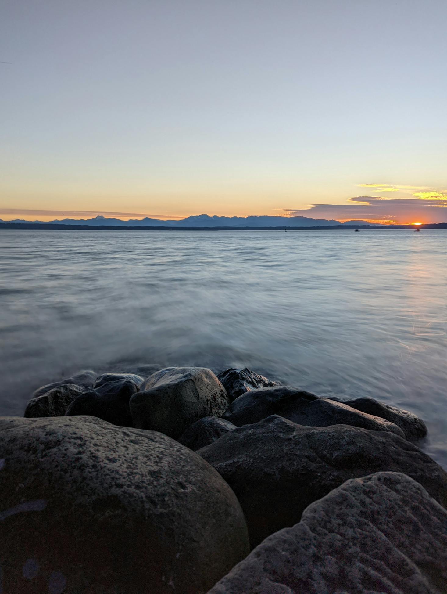 Shoreline rocks and mountains in the distance at sunset on board the Victoria Clipper from Seattle