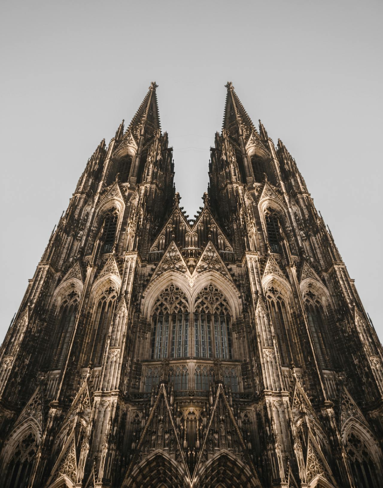 Cologne Cathedral towers against a grey sky in Cologne, Germany.