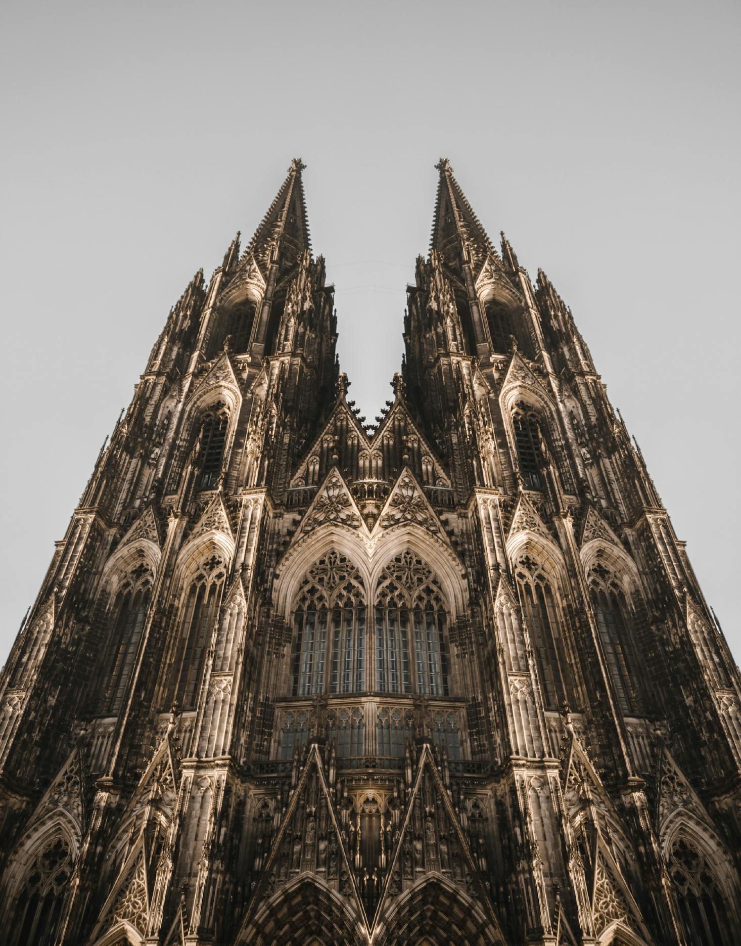 Cologne Cathedral towers against a grey sky in Cologne, Germany.