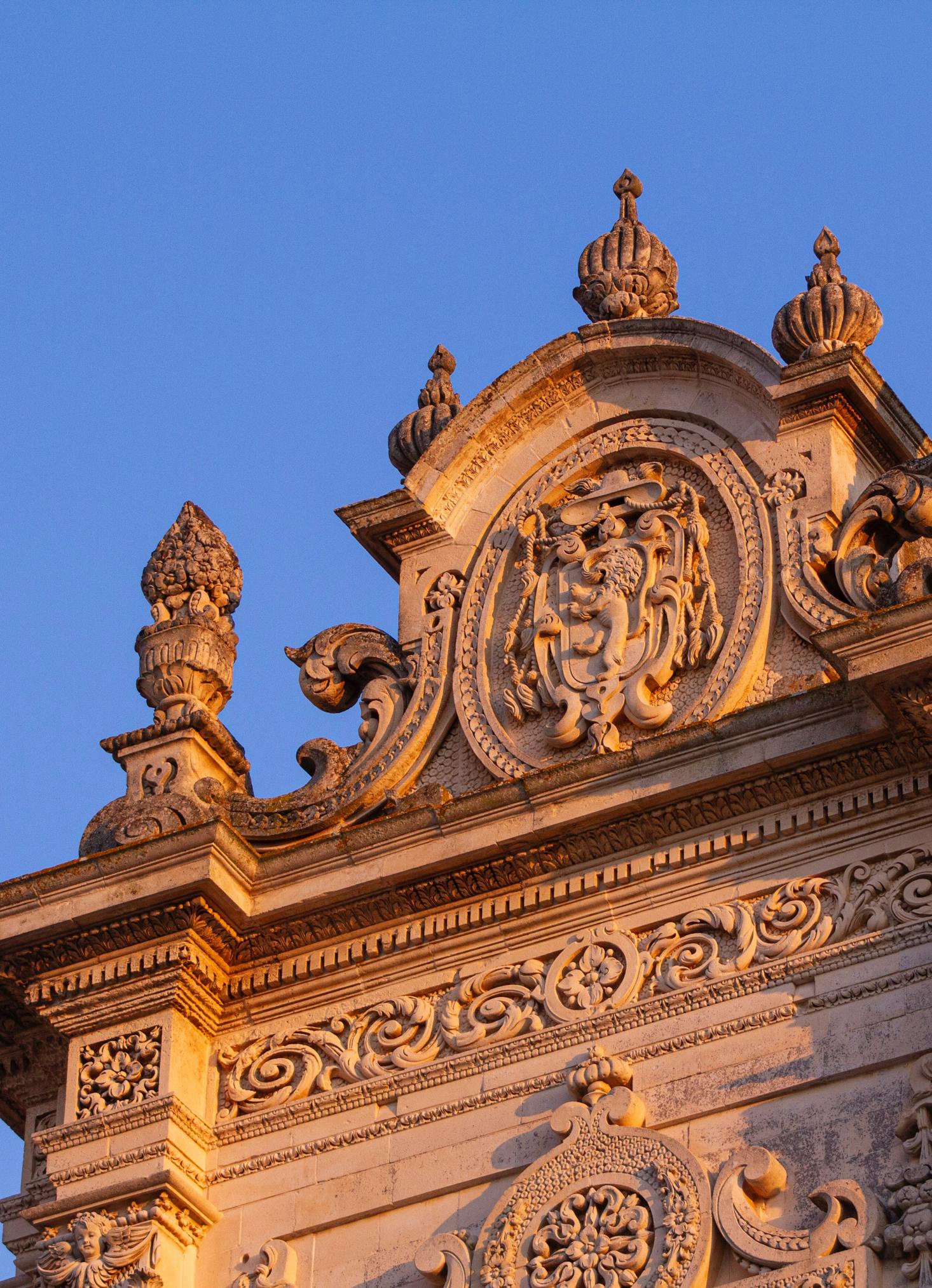 An ancient building is highlighted against a clear blue sky in Lecce, Italy