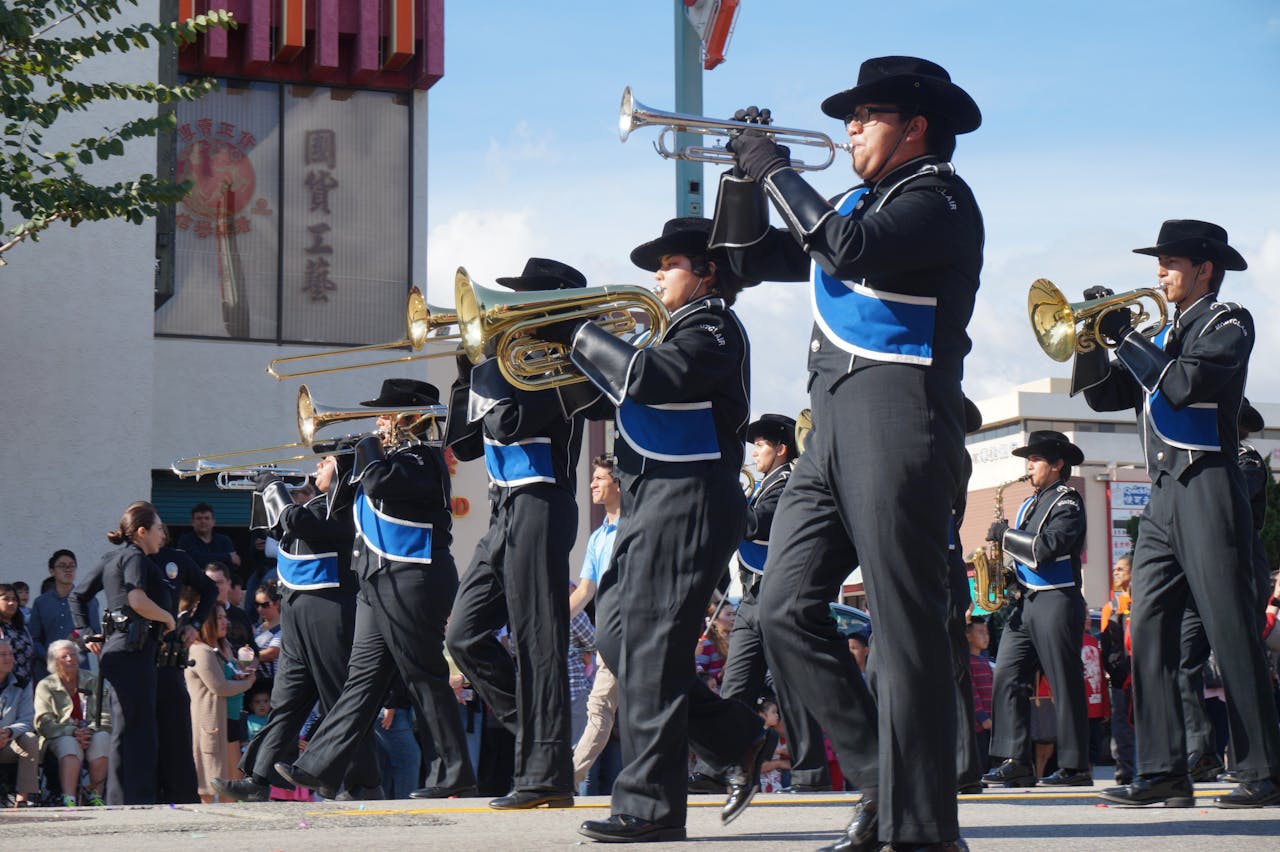 Band members marching in formation down a street as spectators watch from the sidelines