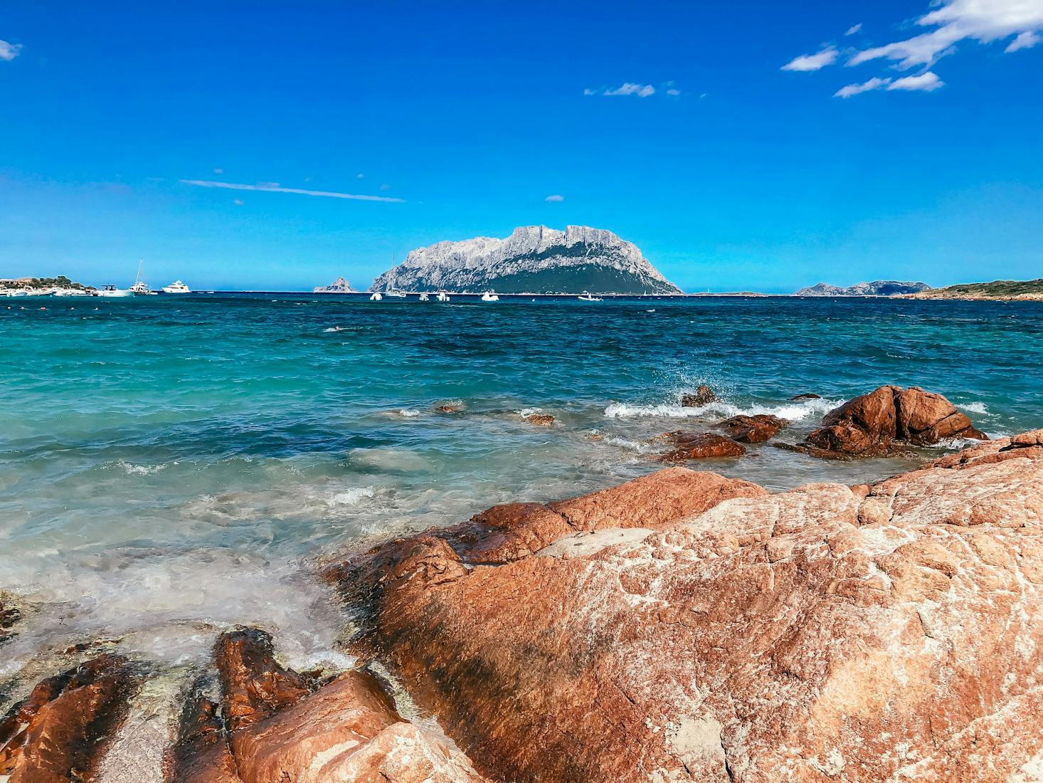 The clear waters and red-tinged rocks of Alghero, Italy