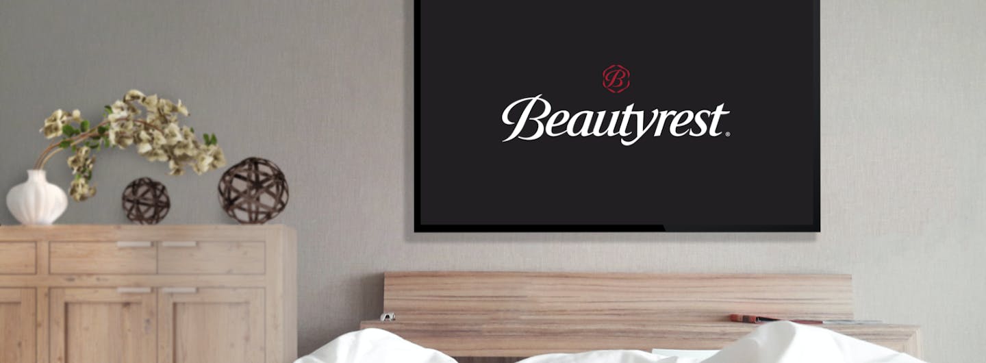 A point of view angle of a person laying in a bed looking at a TV with a Beautyrest logo