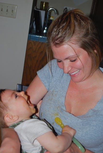 Emily holding Carter trying to feed him, both with big smiles