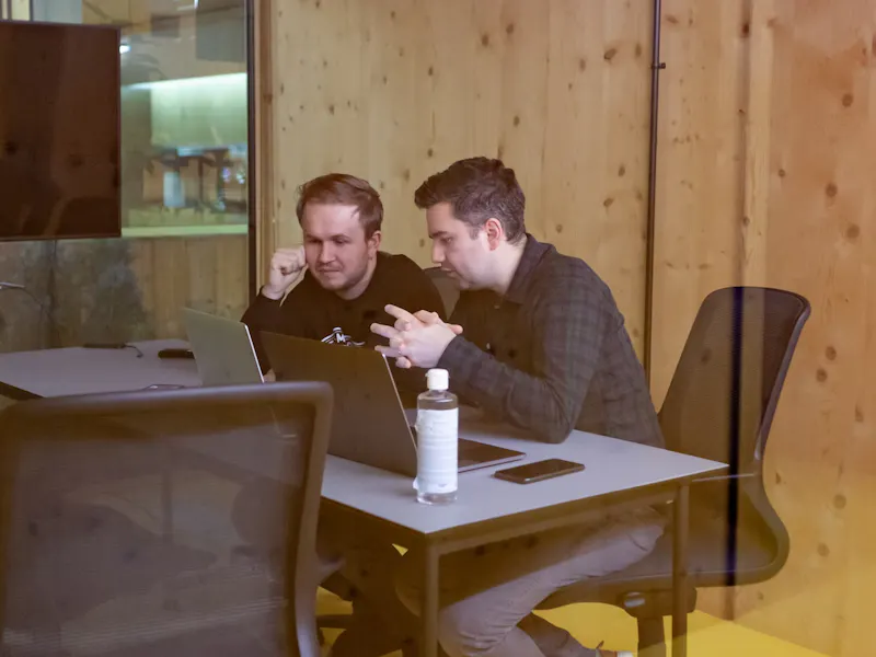 two men discussing something on laptop