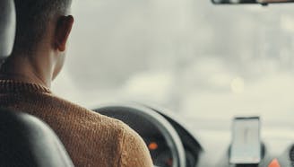 middle aged man in a brown sweater driving a car using gps