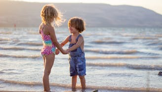 brother and sister at the beach holding hands