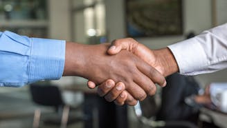 two business professionals shaking hands over deal