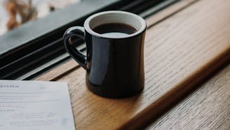 full coffee mug with paper on a wooden windowsill