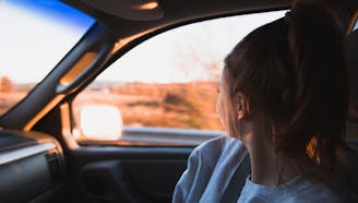 brunette young girl looking out moving car window