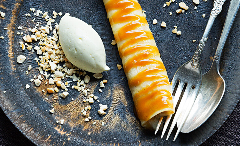 angerichtete grauer Teller mit einer zusammengerollten Crêpe à la Colette, einer Nocke Eis und Besteck