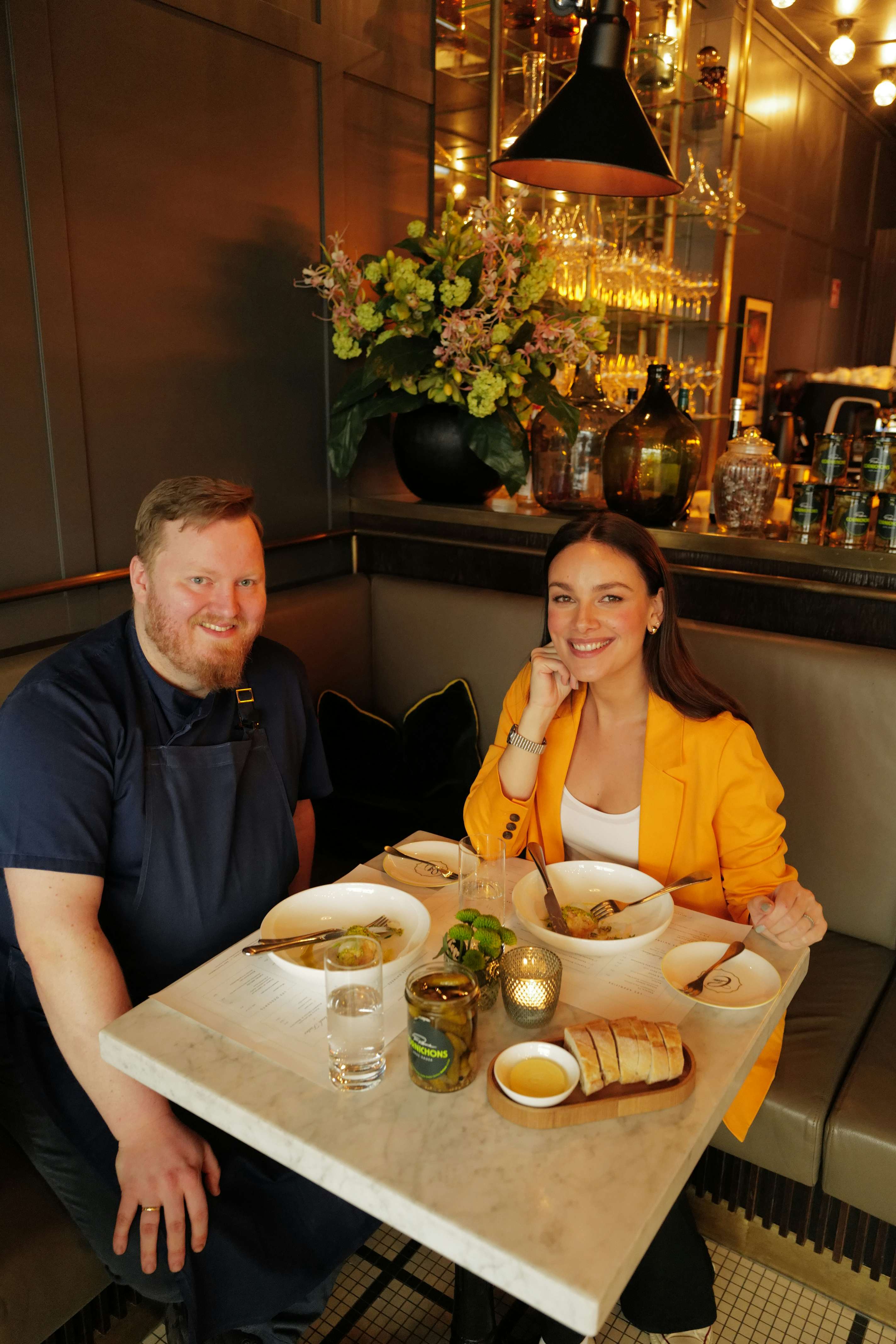 Schauspielerin Janina Uhse und Küchendirektor Dominik Obermeier sitzen an einem gemütlichen Tisch in der Brasserie Colette Tim Raue
