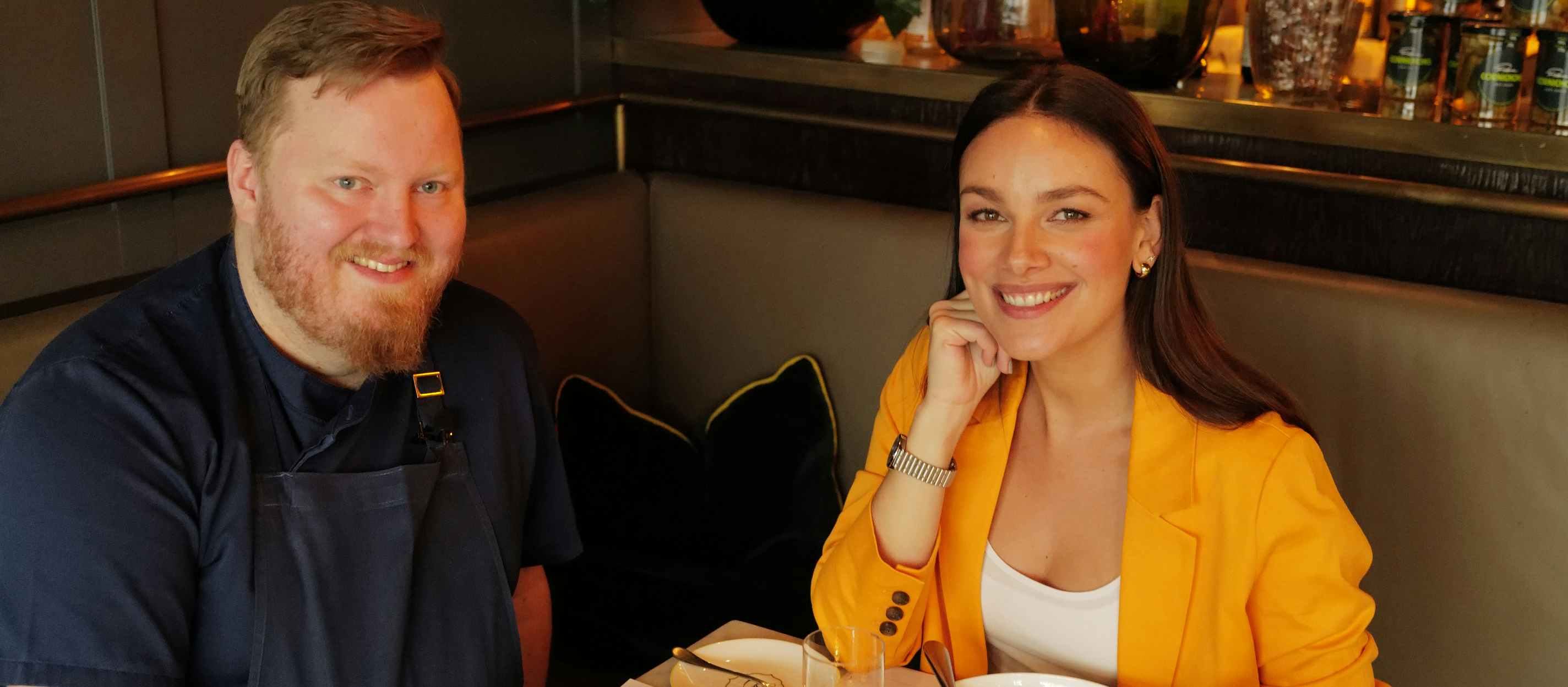 Schauspielerin Janina Uhse und Küchendirektor Dominik Obermeier sitzen an einem gemütlichen Tisch in der Brasserie Colette Tim Raue