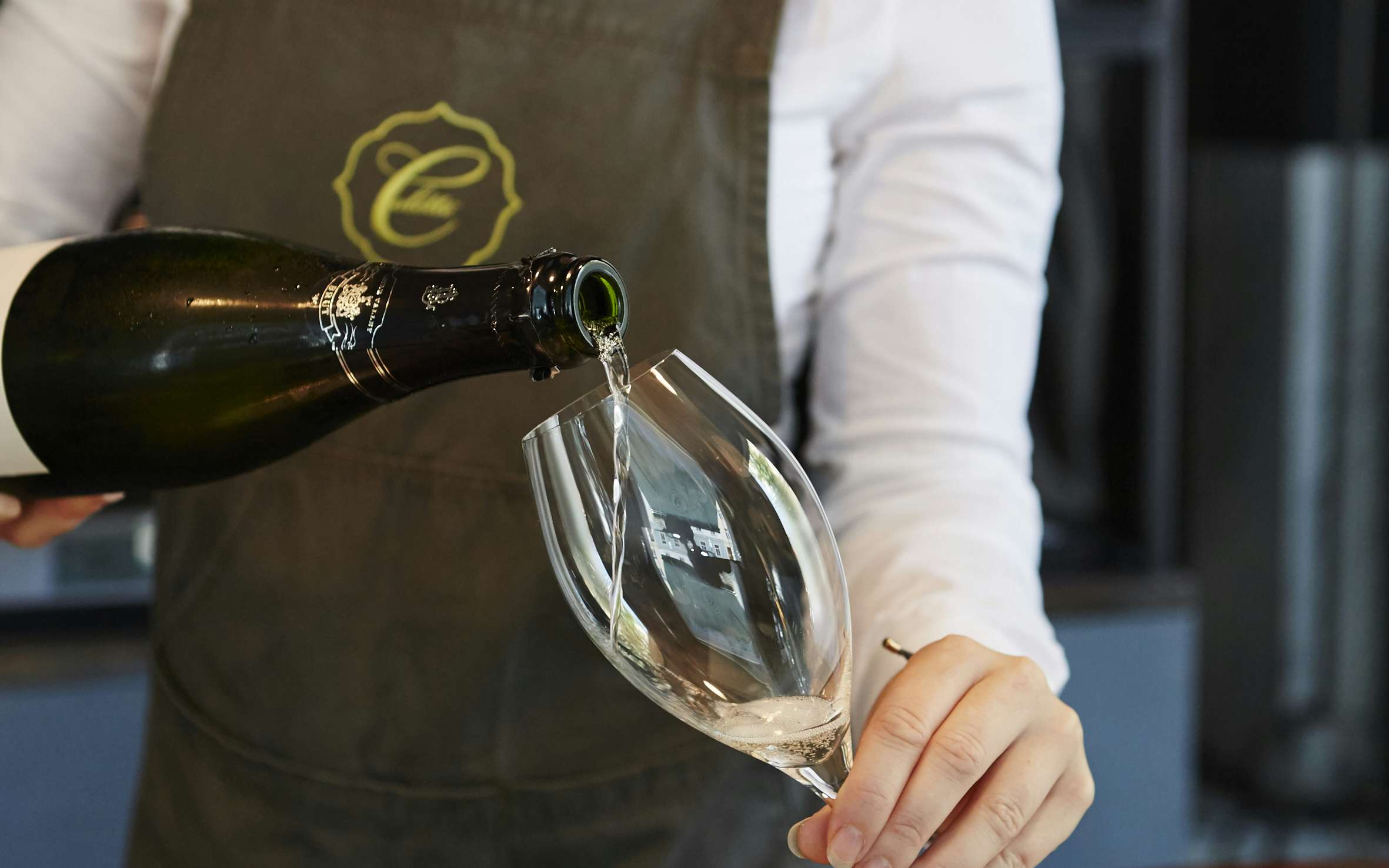 Mitarbeiterin der Brasserie Colette schenkt ein Glas Sekt ein