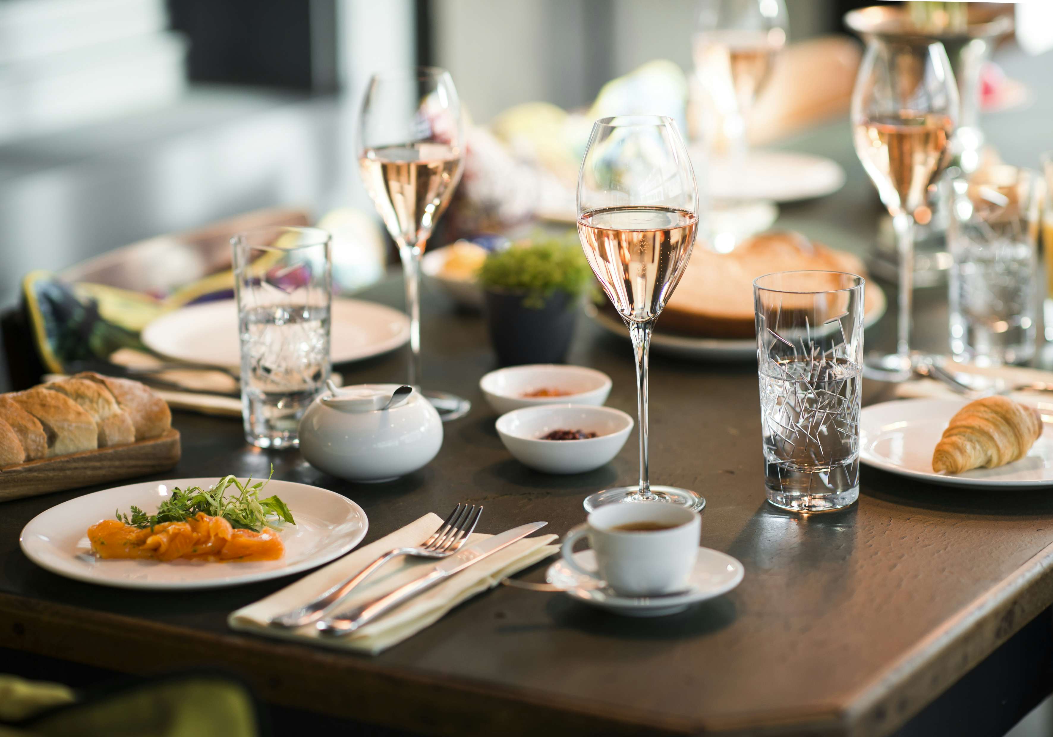 Table with bread, dips, main dishes and sparkling wine at Brasserie Colette by Tim Raue.