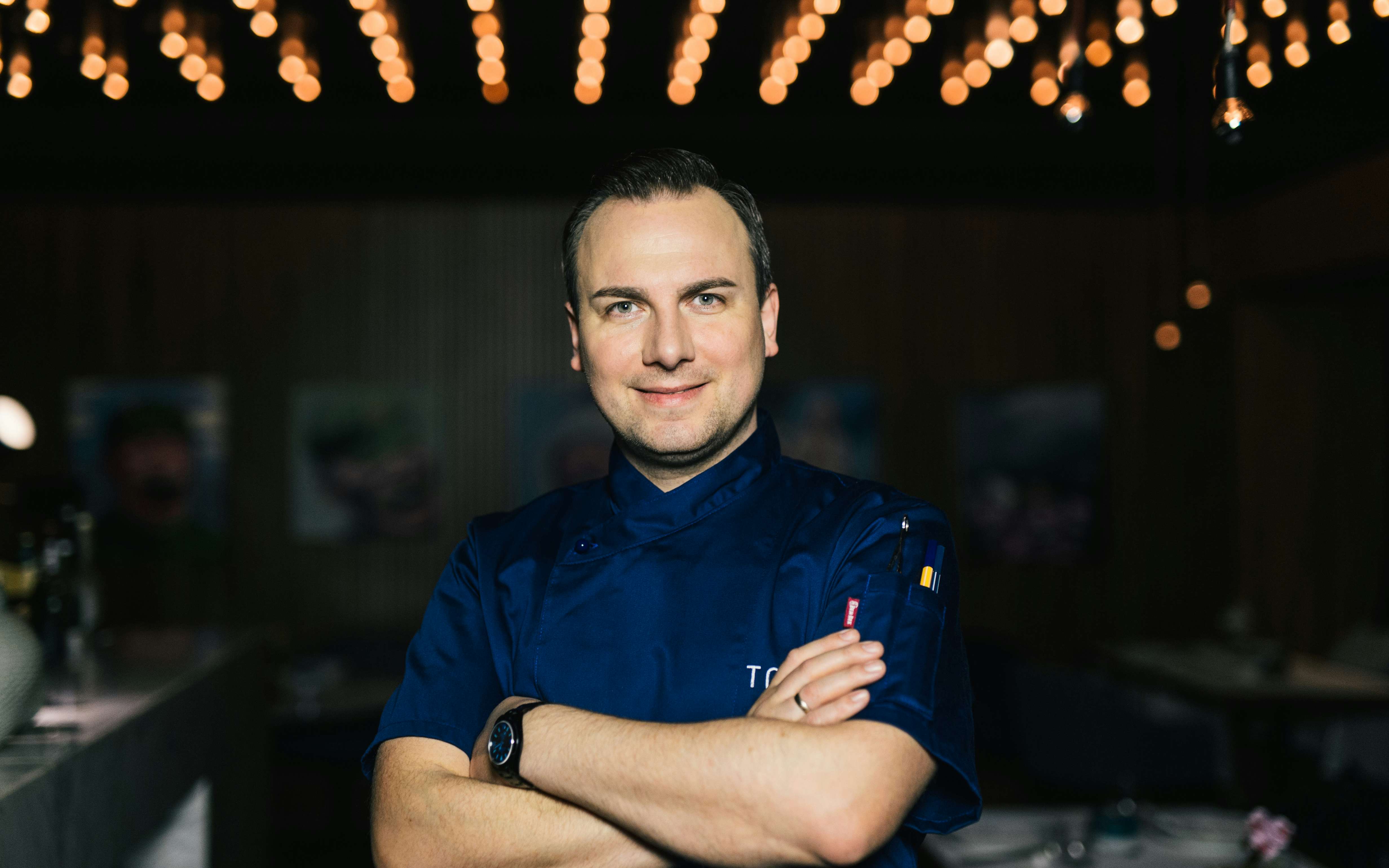 Sternekoch Tim Raue, kulinarischer Berater der Brasserie Colette, steht mir verschränkten Armen lächelnd im Gastraum