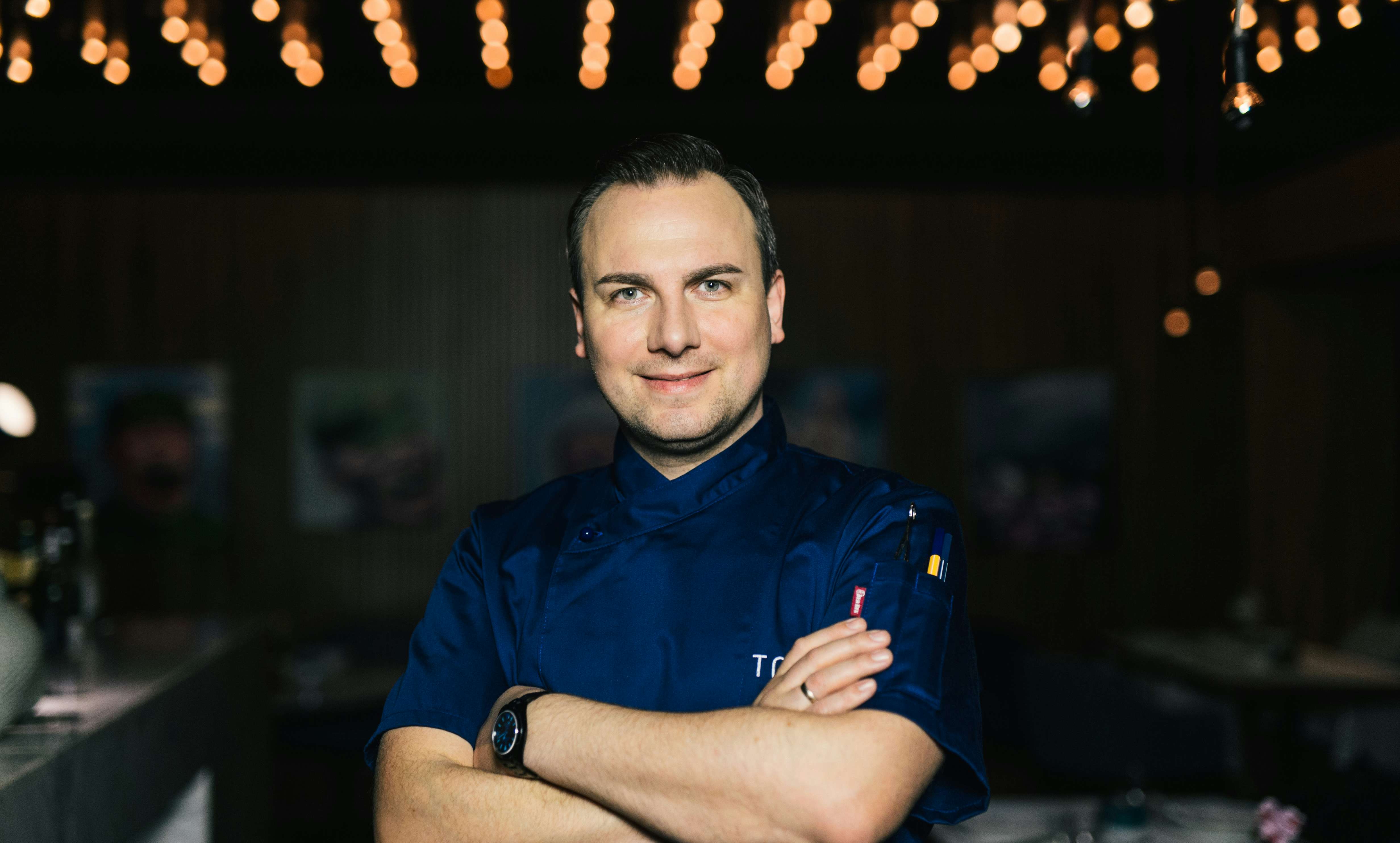 Sternekoch Tim Raue, kulinarischer Berater der Brasserie Colette, steht mir verschränkten Armen lächelnd im Gastraum