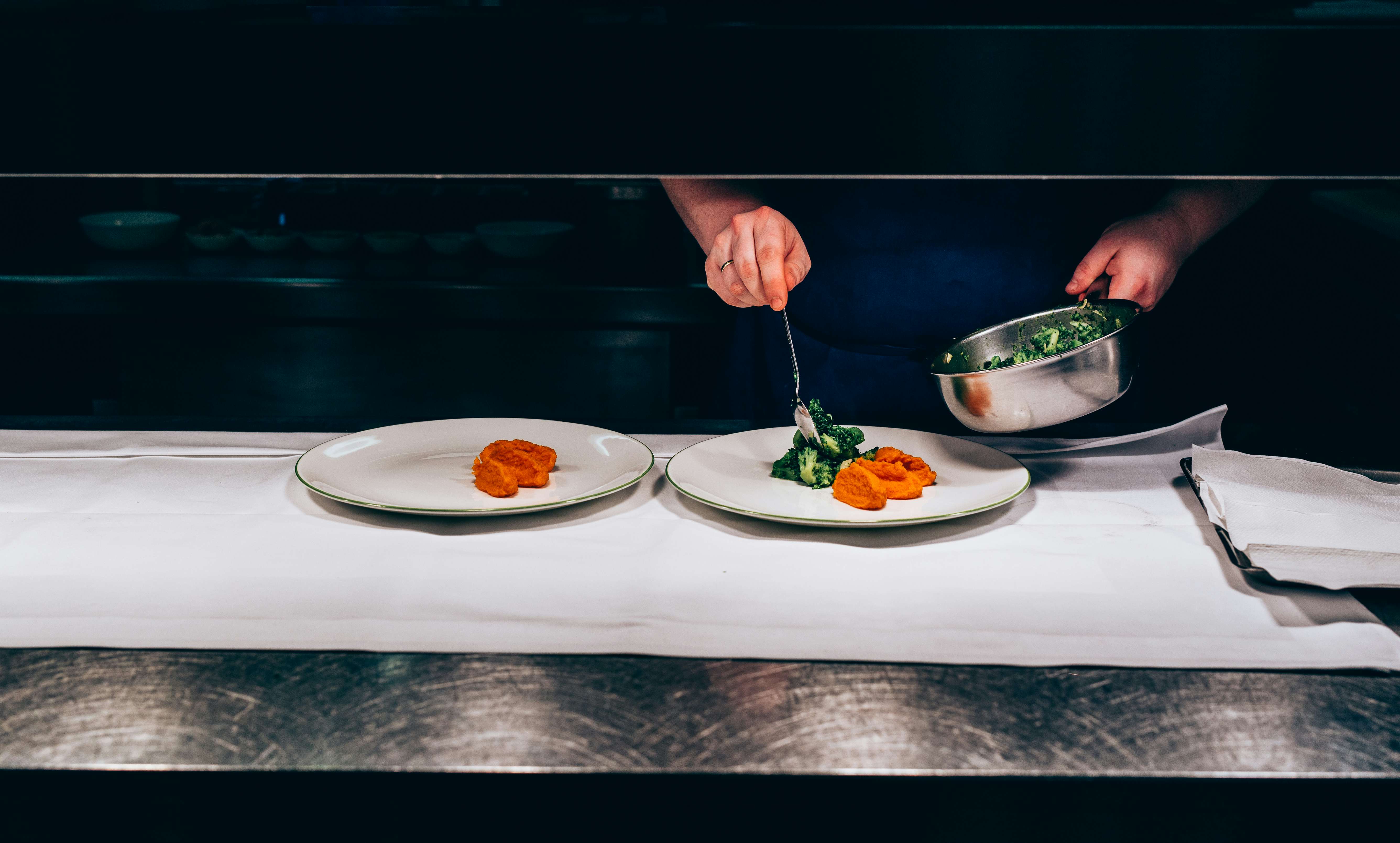 Blick in die Küche der Brasserie Colette - Koch bereitet Speisen auf zwei Teller vor