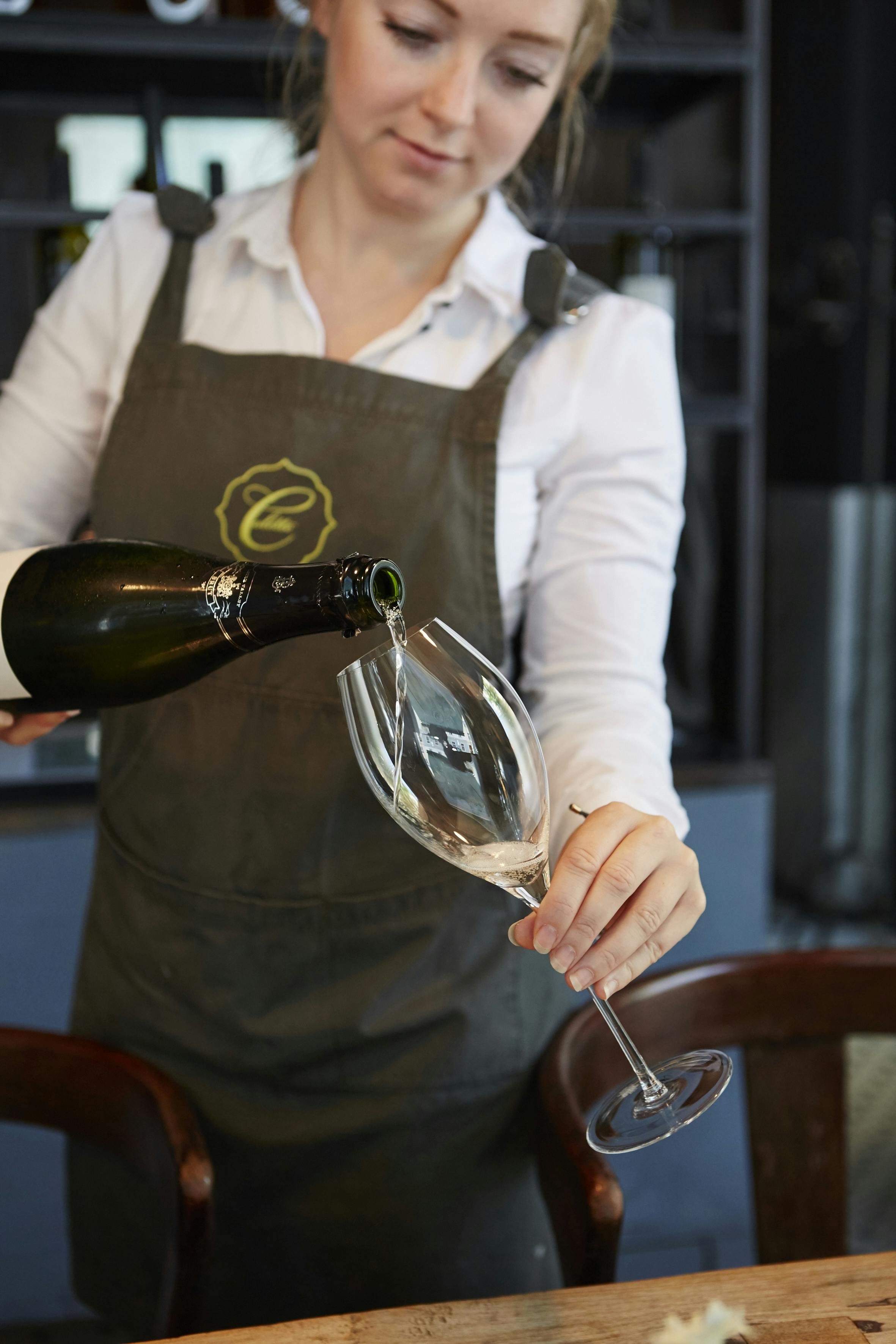 Mitarbeiterin der Brasserie Colette schenkt ein Glas Sekt ein