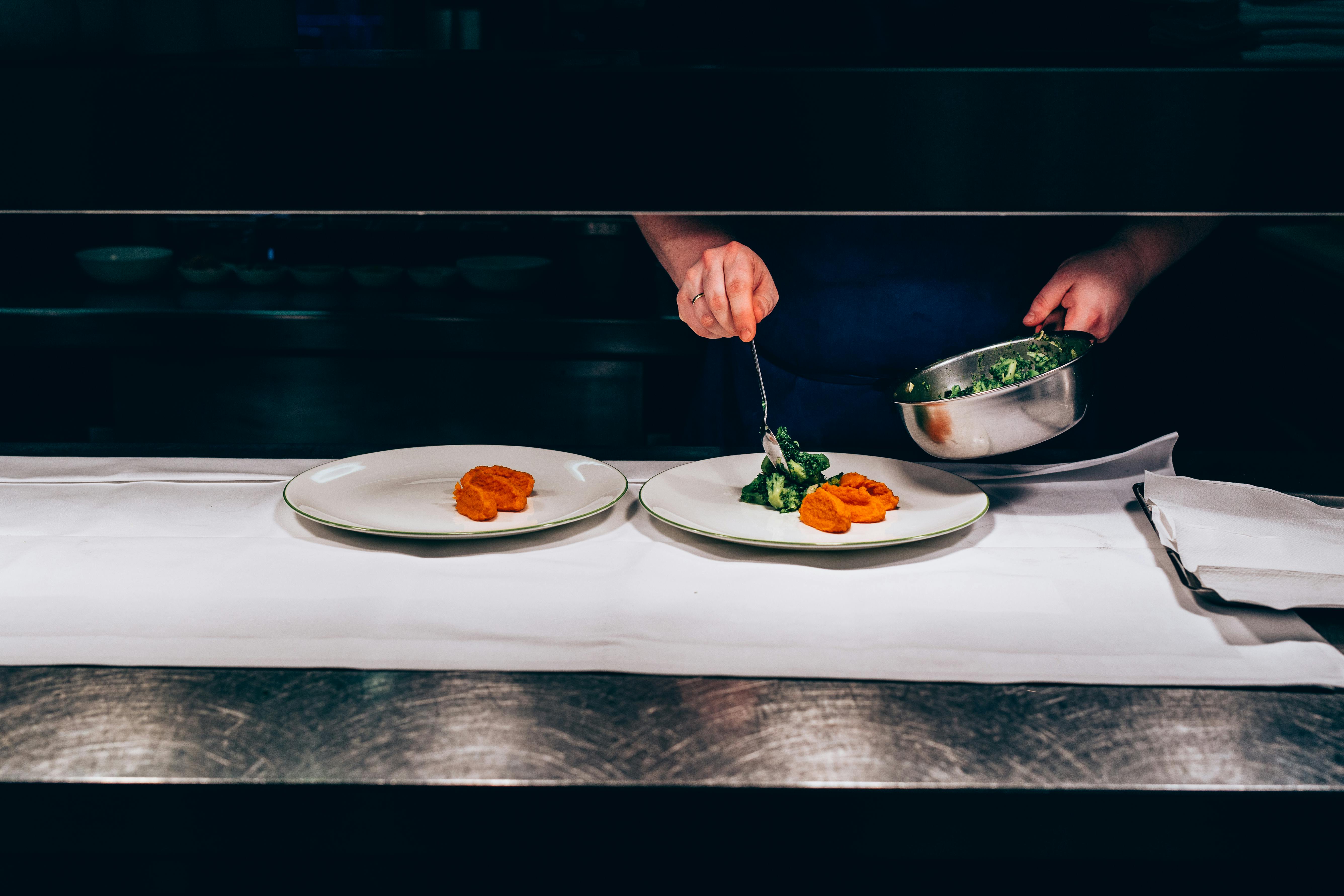 Blick in die Küche der Brasserie Colette - Koch bereitet Speisen auf zwei Teller vor