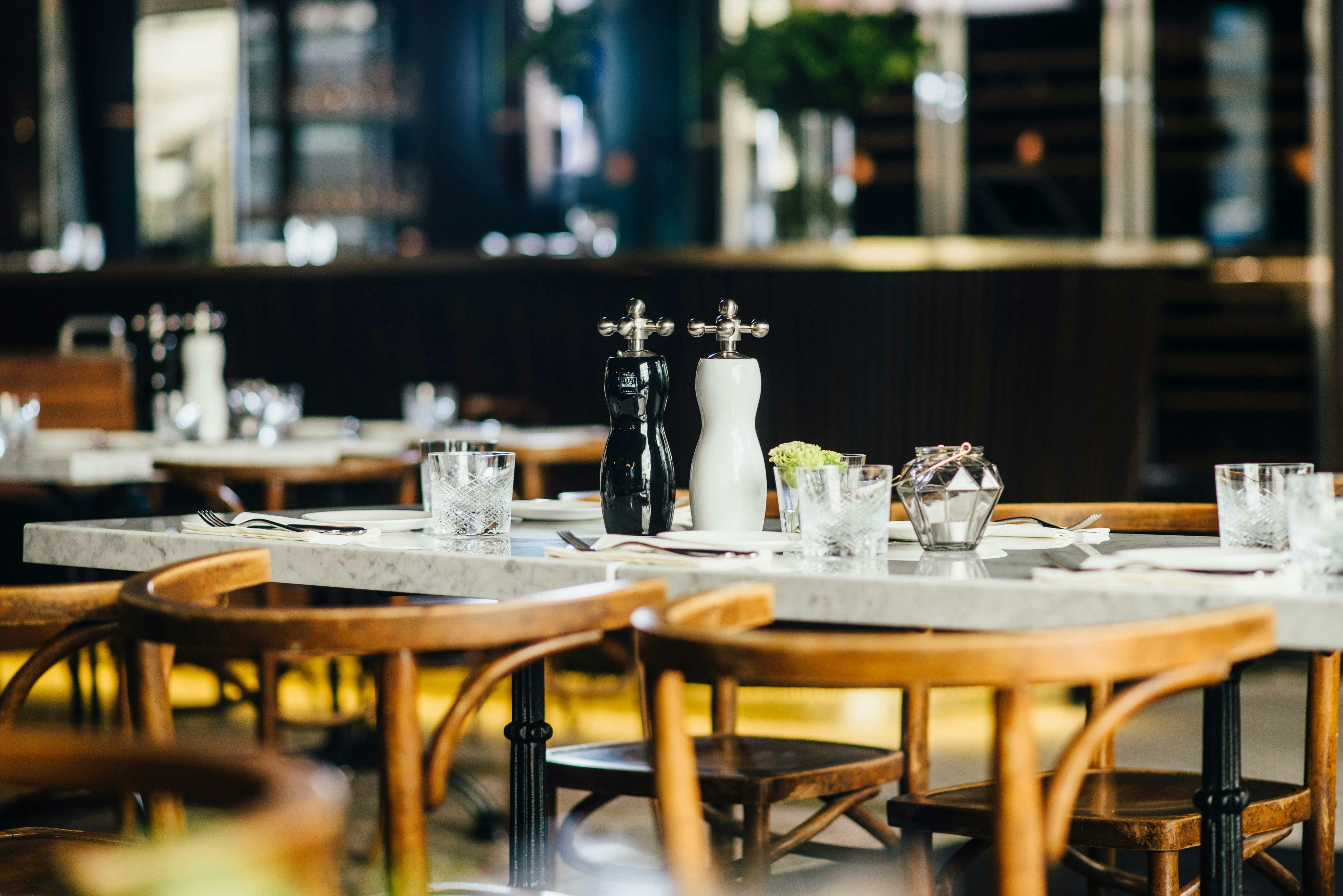 Set table at Brasserie Tim Raue with wooden chairs.