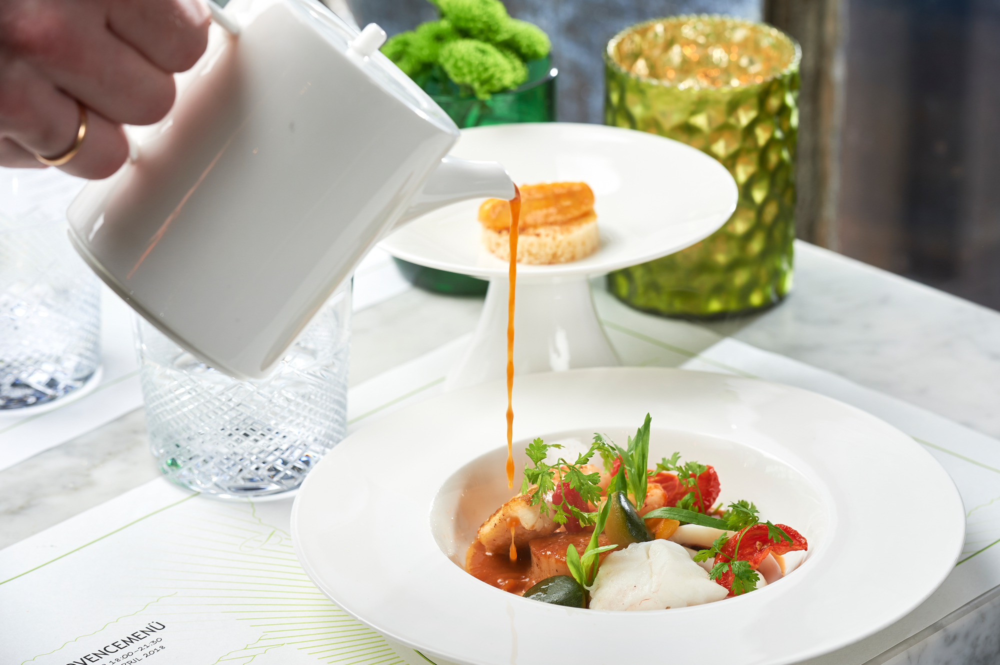 Porzellankanne aus der Sauce auf eine Bodensee Bouillabaisse gegossen wird