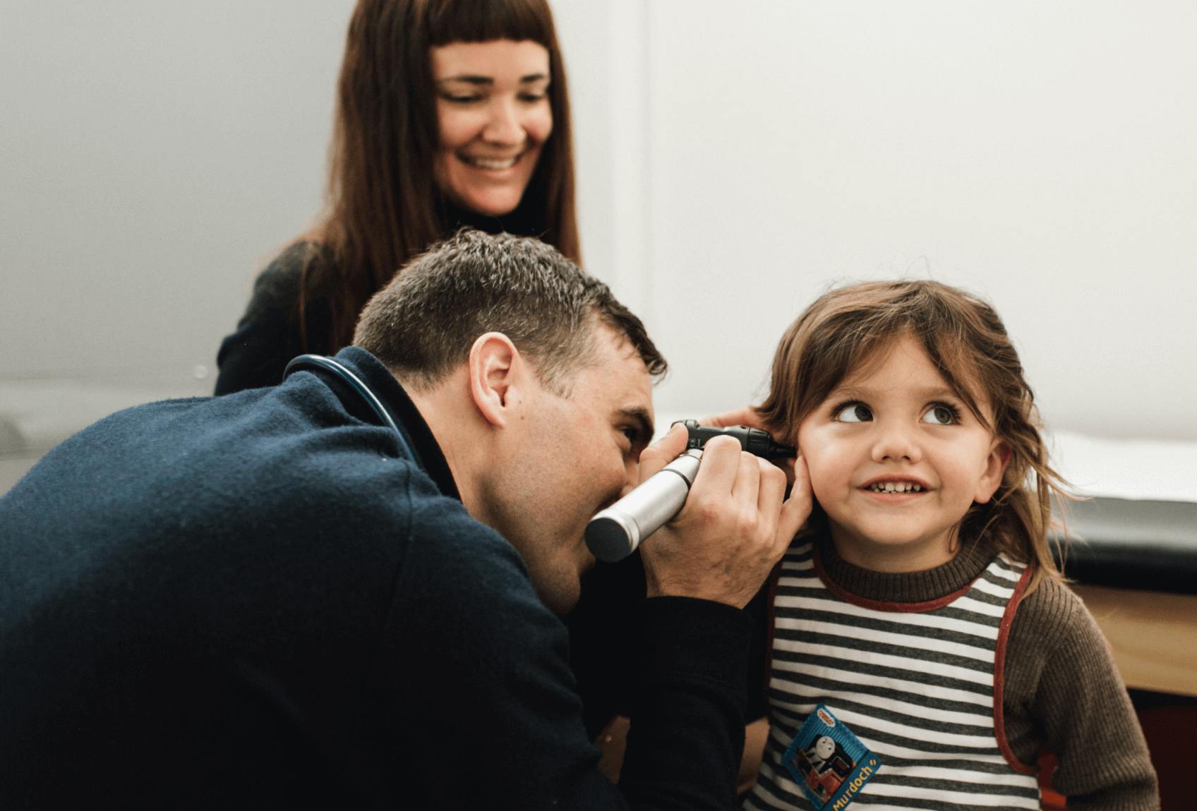 Dr. Corey Fish examines a child's ear with an otoscope.