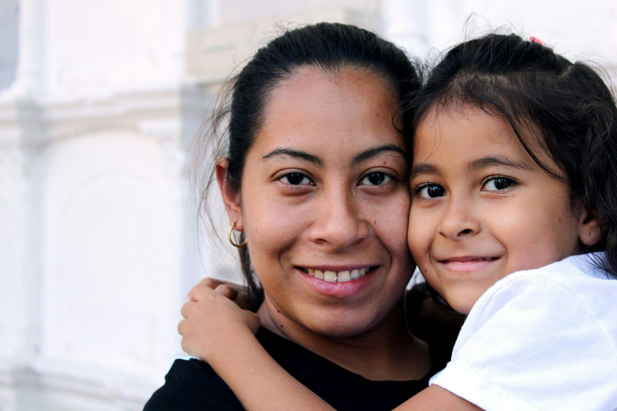 Smiling faces of a child hugging an adult. 