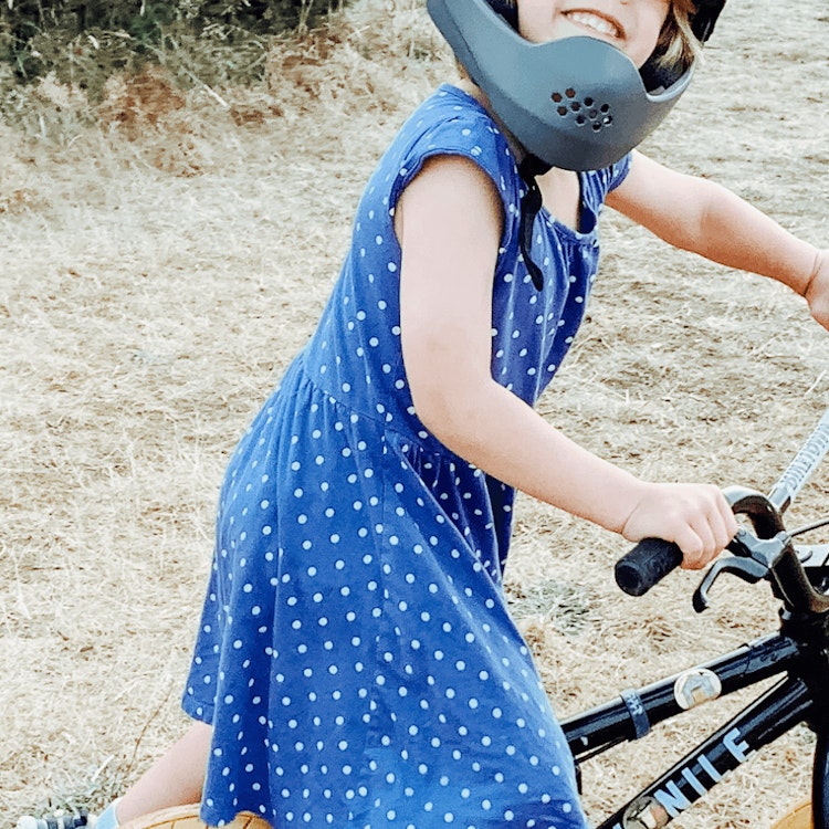 Picture of smiling child wearing a helmet on a bicycle