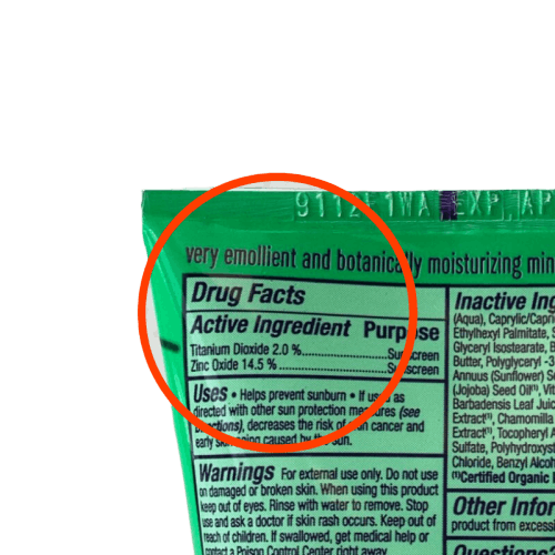 A portion of a sunscreen bottle showing with a red circle around the active ingredients of titanium dioxide and zinc oxide.