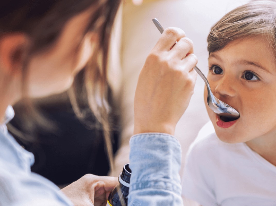 Parent giving meds with spoon in child's mouth