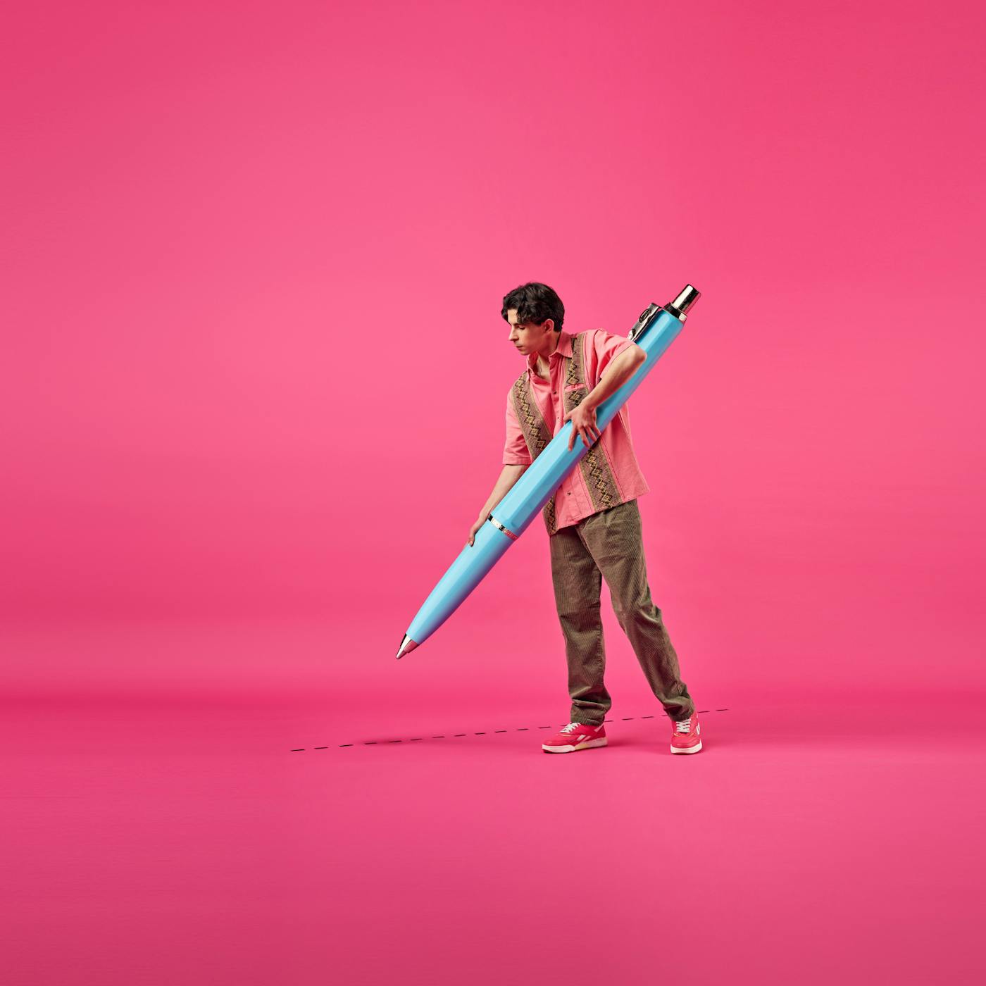 Man med en stor penna, rosa bakgrund.